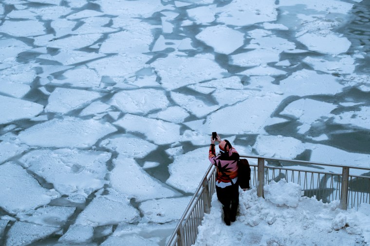 Image: A pedestrian stops to take a photo by Chicago River as bitter cold phenomenon called the polar vortex has descended on much of the central and eastern United States