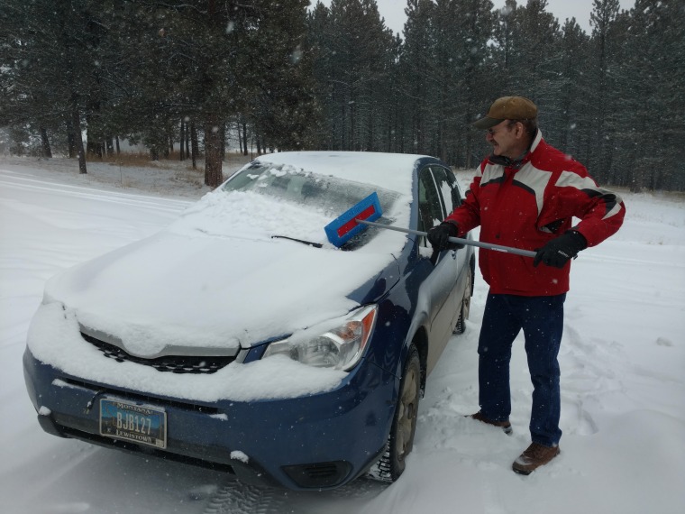 Mel Jackson cleaning snow off of his wife's Subaru Forester.
