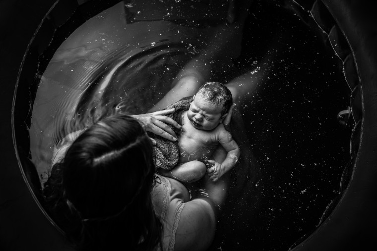 It almost seems as if time stood still in this picture of a mom gazing at her newborn in a birthing pool. It won first place in the black and white photography category of the 2019 Birth Becomes Her Image Contest.