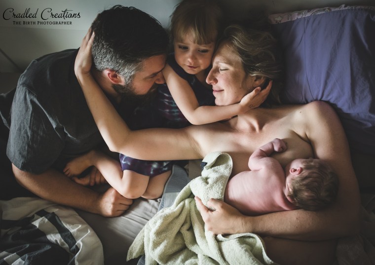 In this third place out of hospital image, a family embraces as the newest addition breastfeeds.