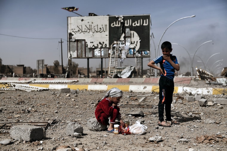 Image: Iraqi children in the Nablus neighborhood of Mosul, Iraq, near an Islamic State billboard on March 12, 2017.