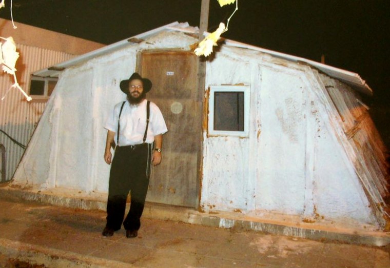 Image: Shabtay Bendet stands in front of a makeshift building in a West Bank settlement in 2002