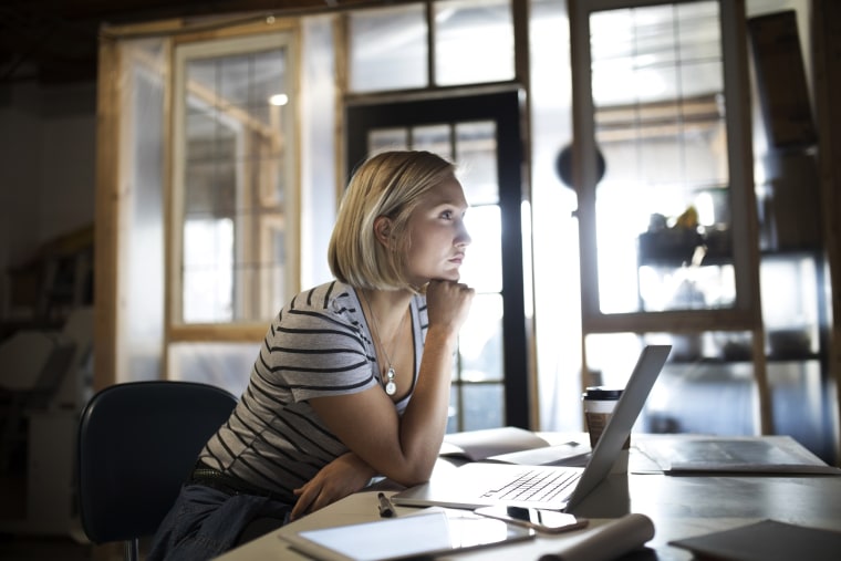 Pensive, focused woman working at laptop in office