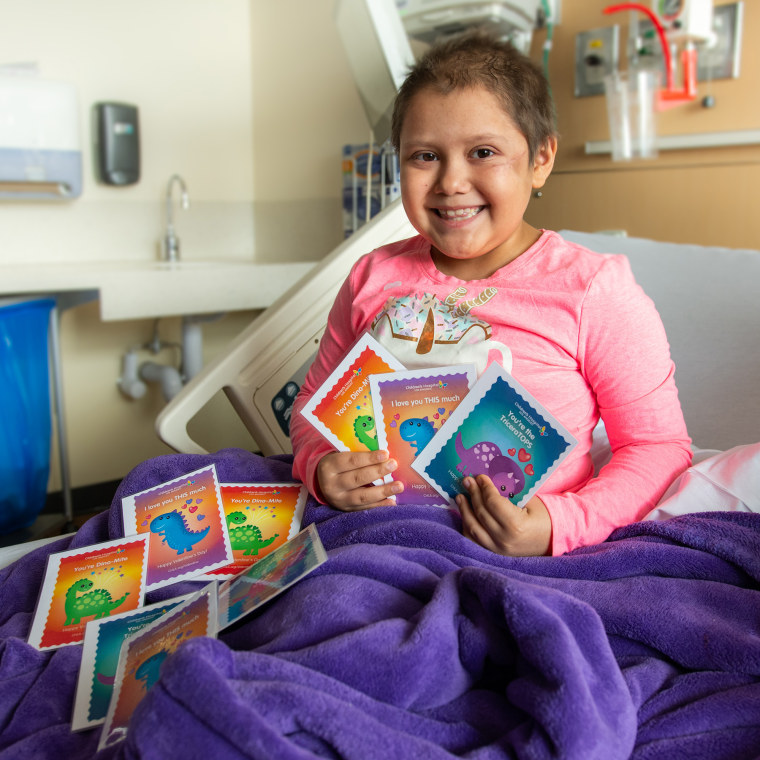 Lylah, an 8-year-old patient at Children’s Hospital Los Angeles, holds up some of the sweet dinosaur-themed Valentine’s Day cards she and others will receive.  (photo by Owen Lei)