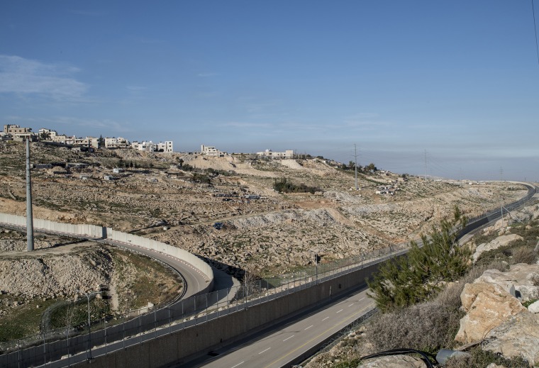 Image: The entrance of a highway that carves a path from the outskirts of Jerusalem through hills to toward the northern West Bank