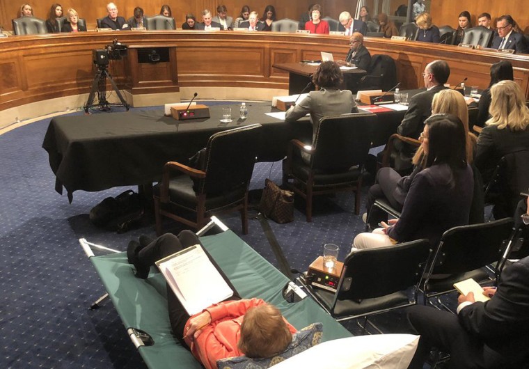 A woman testifies from a cot at Senate hearing on managing pain during the opioid crisis on Feb. 12, 2019.