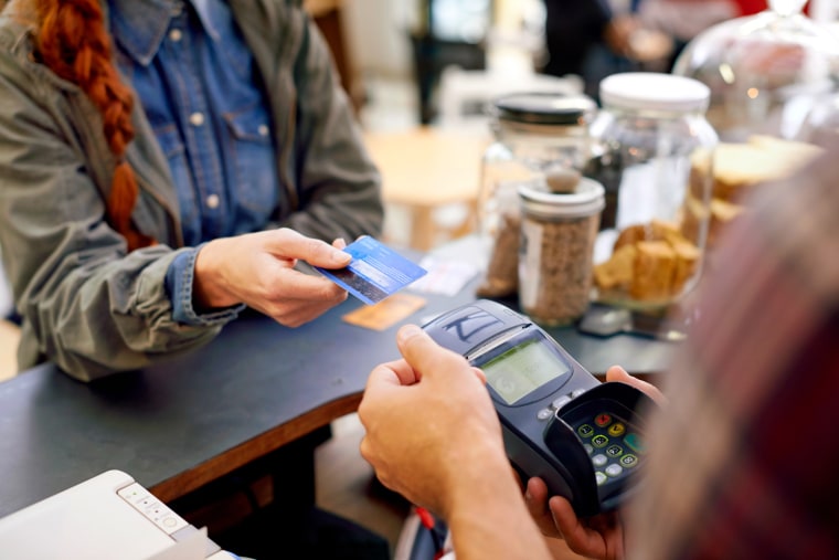 Image: A customer pays for her order with a credit card in a cafe