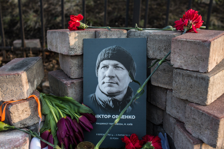 Image: A photograph of Viktor Orlenko is displayed at a makeshift memorial 