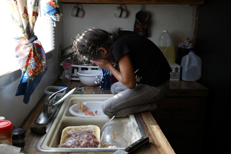Image: Rachel, a migrant from Honduras, takes a break from washing a doll in the sink in Texico