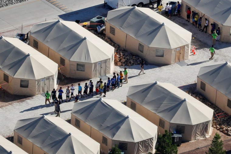 Image: Immigrant children housed in a tent encampment under the new \"zero tolerance\" policy by the Trump administration are shown walking in single file at the facility near the Mexican border in Tornillo, Texas