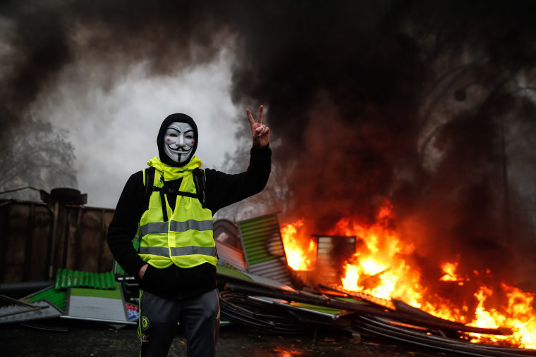 Image: A masked "yellow vest" protester near a burning barricade in Paris on Dec. 1.