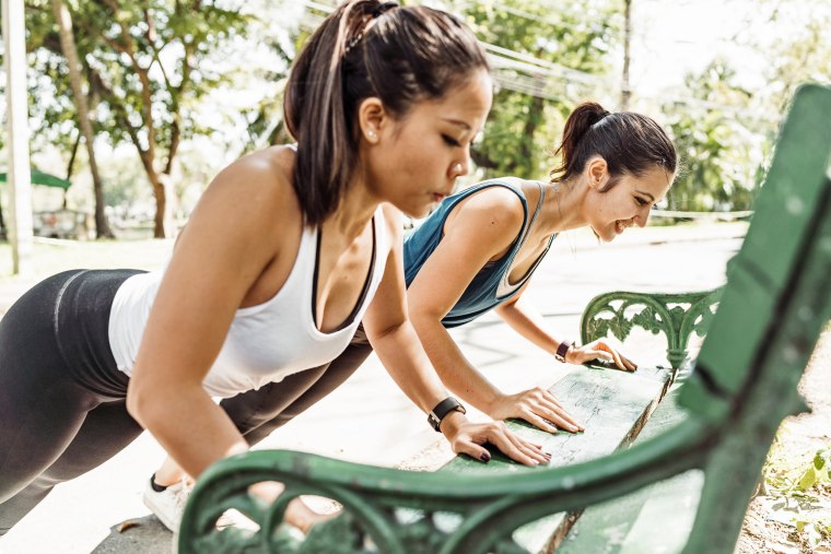 Young women doing pushups together outdoor at the park