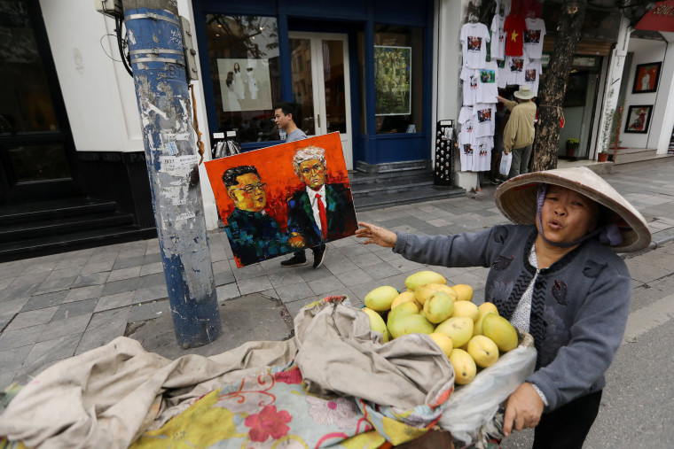 Image: A man walks past a vendor while holding a painting of North Korean leader Kim Jong Un and U.S. President Donald Trump ahead of the North Korea-U.S. summit in Hanoi