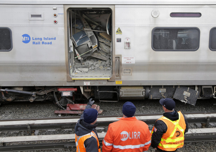 Image: Emergency personnel look over a train that derailed after striking a vehicle in Westbury