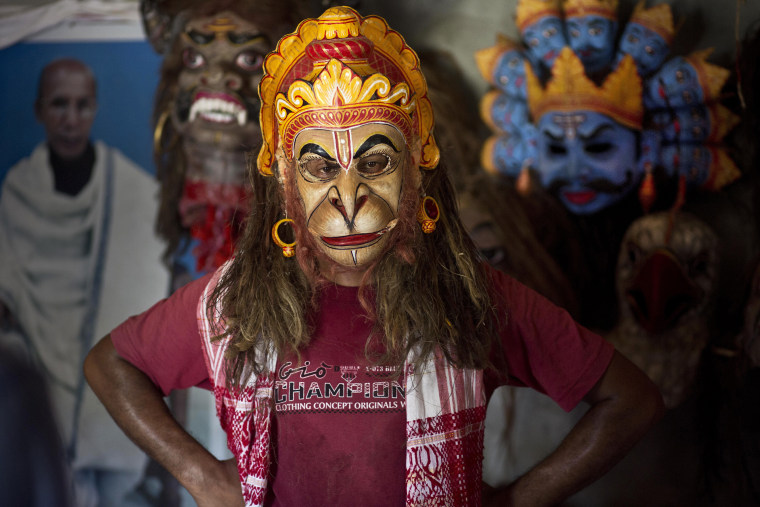 A mask maker wears a mask of Hindu monkey god Hanuman in India