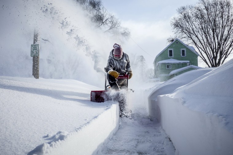 Image: Michael Mueller snow blows the sidewalk near his house in Rochester
