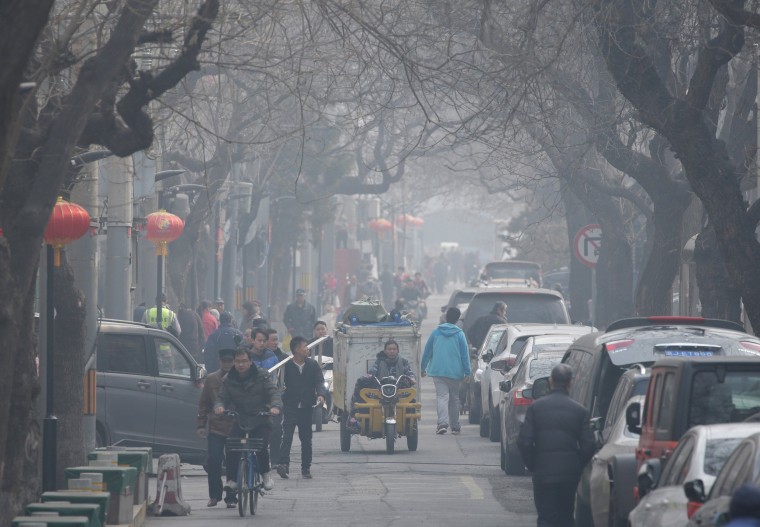 Image: People are seen in a traditional alleyway on a polluted day in central Beijing