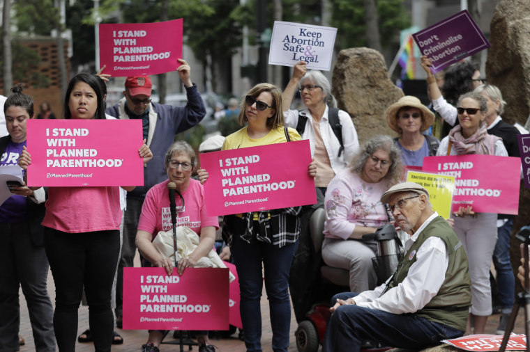 Protesters hold signs supporting Planned Parenthood in Seattle, as they demonstrate against President Donald Trump and his choice of federal appeals Judge Brett Kavanaugh as his second nominee to the Supreme Court, on July 10, 2018.