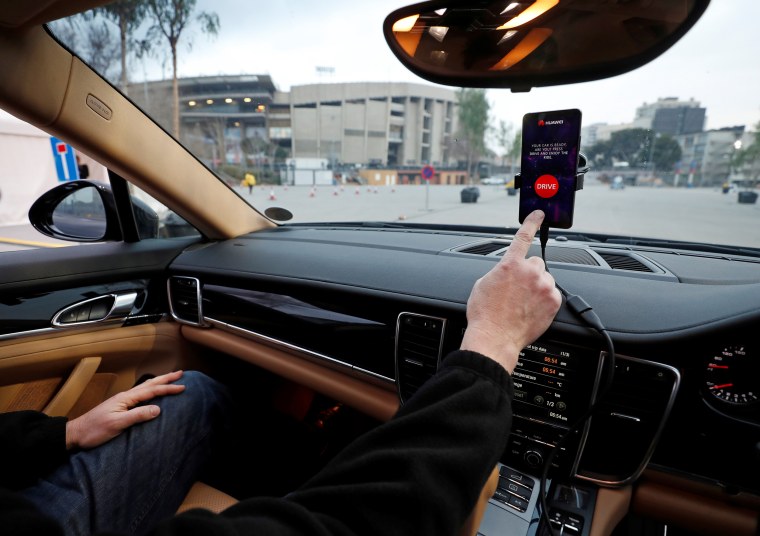 An engineer points to a Huawei Mate 10 Pro mobile used to control a driverless car during the Mobile World Congress in Barcelona