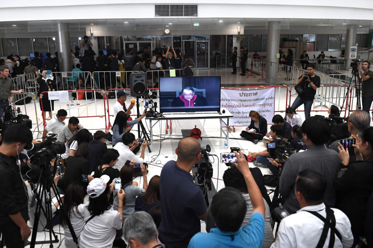 Image: Journalist records a live TV broadcast of a judge delivering the decision of the Constitutional Court in Bangkok to dissolve the Thai Raksa Chart party