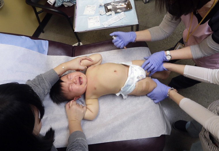 Image: One-year-old Abel Zhang cries as he receives the last of three inoculations, including a vaccine for measles, mumps, and rubella (MMR), at the International Community Health Services