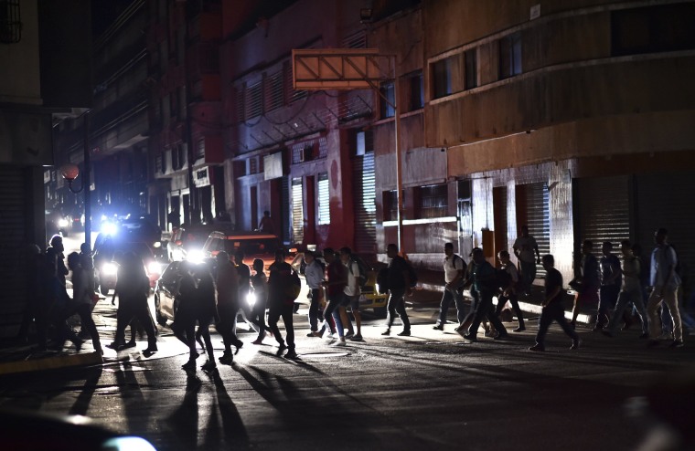 Image: People cross a street during a power cut in Caracas, Venezuela