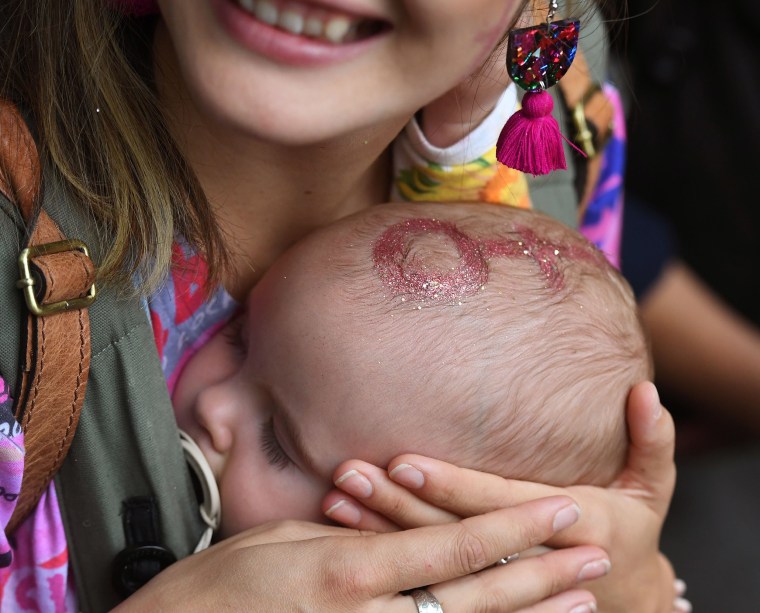 Image: A woman holds her baby close as thousands march to mark International Women's Day in Melbourne, Australia