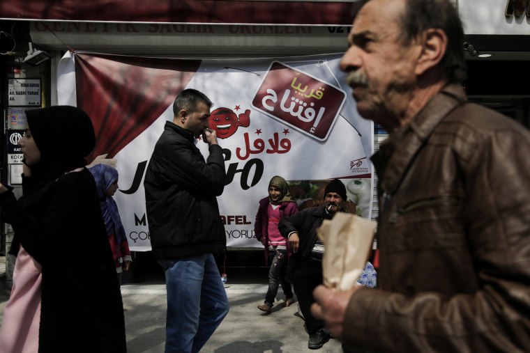 Passersby walk past an Arabic sign for a falafel shop in Istanbul's "Little Syria" neighborhood.