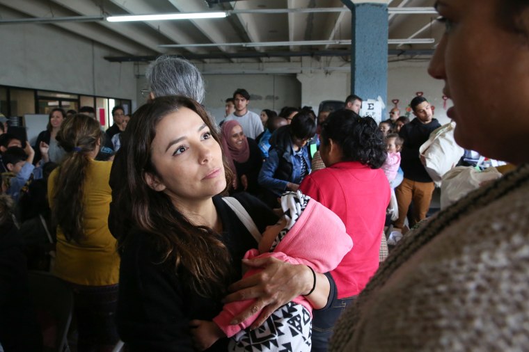 Image: Eva Longoria holds a baby while speaking to the mother at a migrant shelter in Tijuana, Mexico.