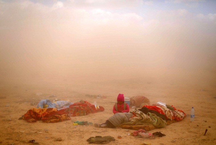 Image: Children sit next to their injured mother near the village of Baghouz
