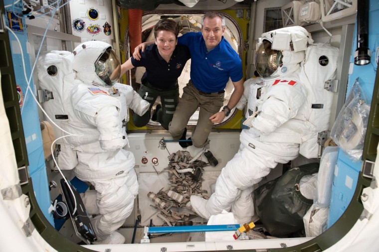 Image: Astronauts Anne McClain and David Saint-Jacques are pictured in between a pair of spacesuits that are stowed and serviced inside the Quest airlock where U.S. spacewalks are staged.