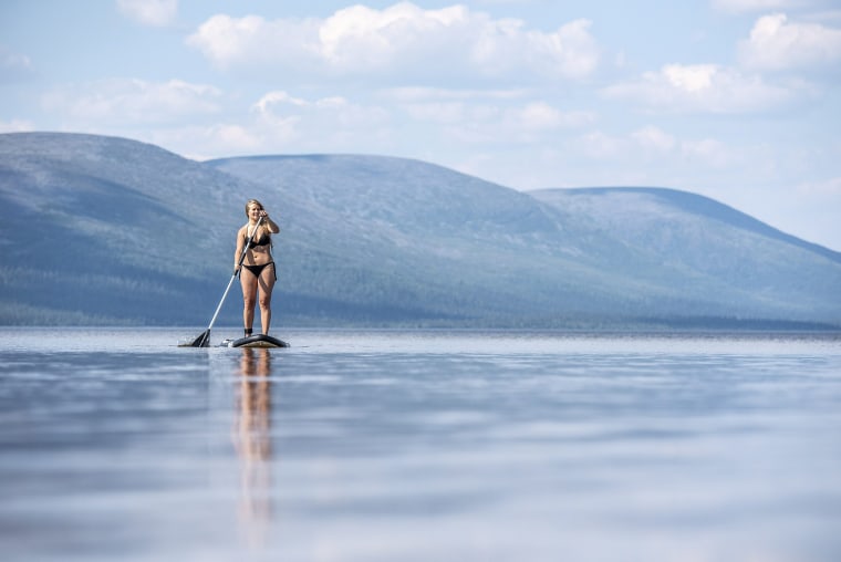 Image: A woman enjoys the warm weather while paddling on the Pallasjarvi lake in Kittila, Lapland