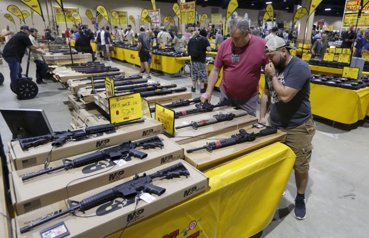 Image: With a variant of the AR-15 in the foreground, patrons peruse weapons at a gun show in Miami, Florida on Feb. 17, 2018.