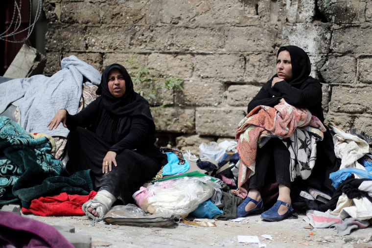 Image: Palestinians sit with their belongings in a street outside their destroyed house in Gaza City