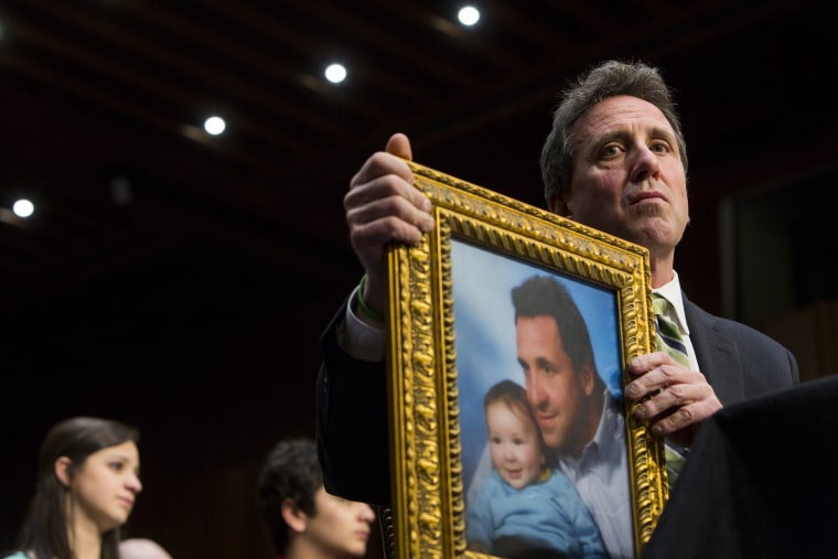 Image: Neil Heslin holds a photo of him and his son, Jesse, while testifying before the Senate Judiciary Committee in Washington in 2013.