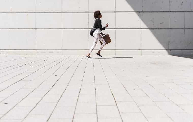 Running businesswoman with smartphone and briefcase