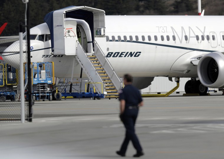 Image: A worker walks next to a Boeing 737 MAX 8 airplane parked at Boeing Field