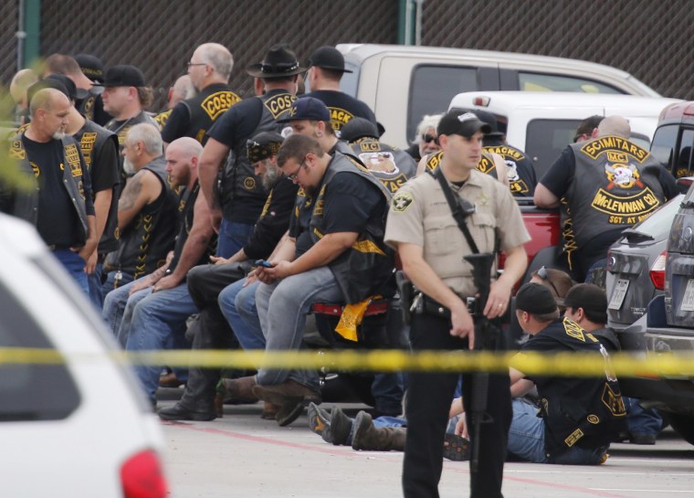 Image: A McLennan County deputy stands guard near a group of bikers