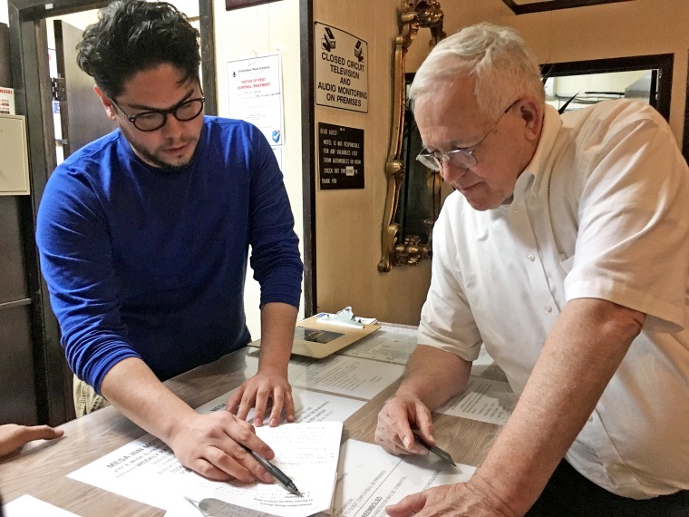 Ruben Garcia, Annunciation House executive director and founder, reviews with general manager Chris Acuna, costs of hotel rooms and ballroom space for immigrants who have come to the border and been released by Customs and Border Protection.