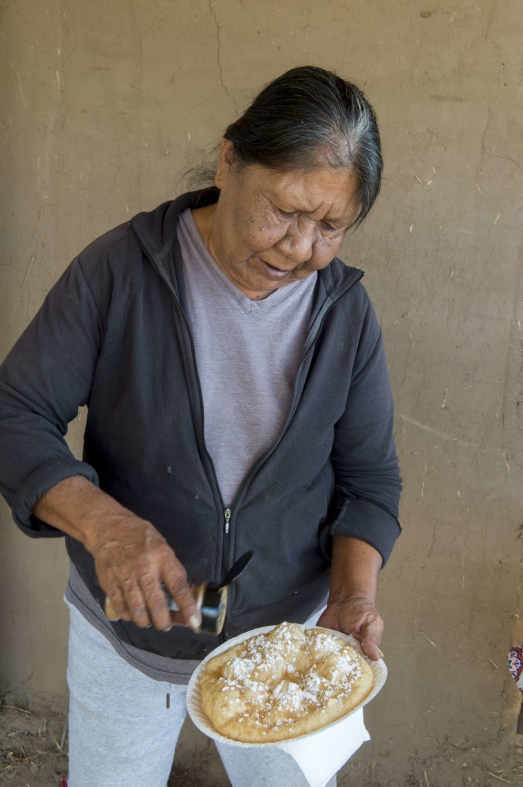 A native American woman is making Indian fry bread in front