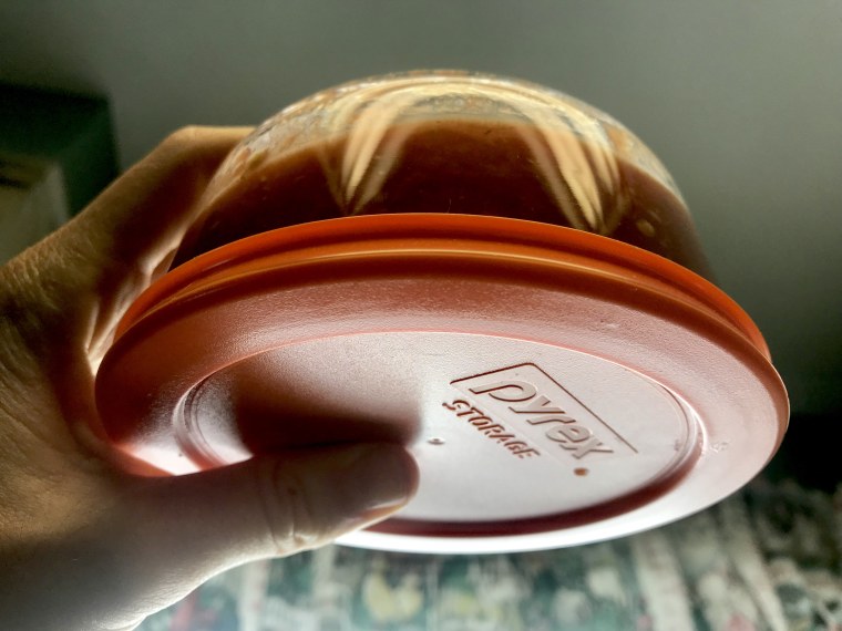 Holding a Pyrex glass storage container filled with salsa upside down