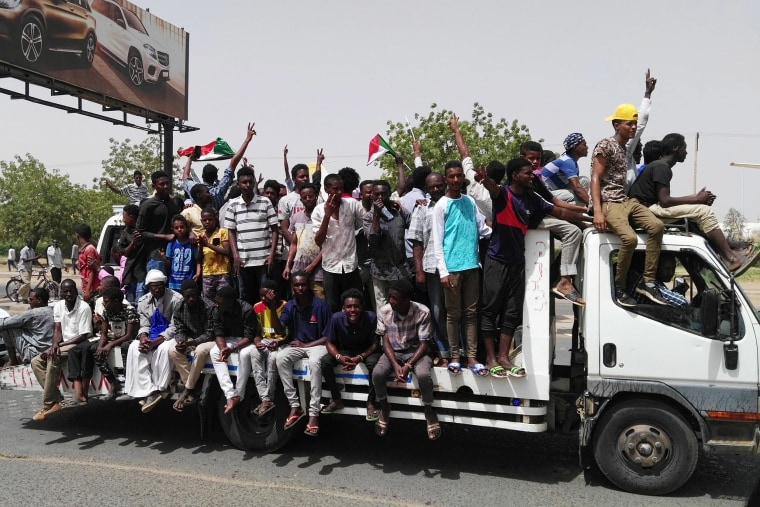 Image: Sudanese men celebrate while rallying in the capital Khartoum
