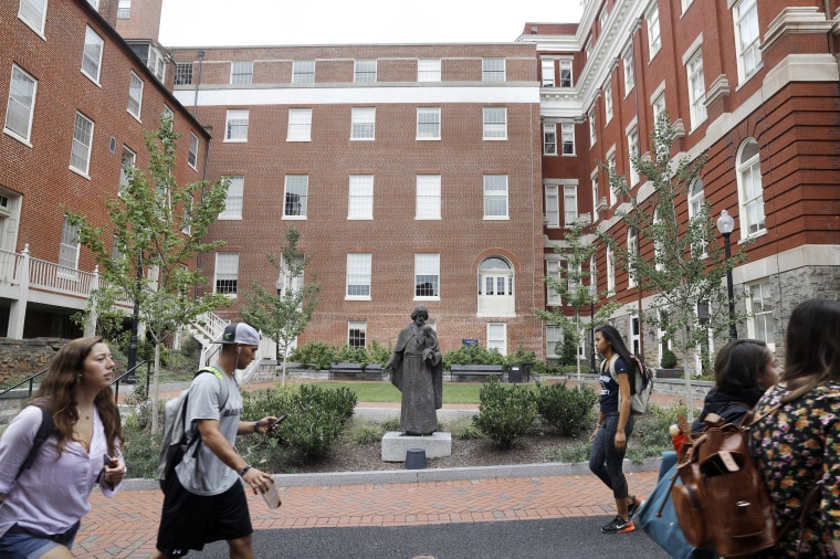 Image: Students walk past a Jesuit statue in front of Freedom Hall, center, formerly named Mulledy Hall, on the Georgetown University campus in Washington