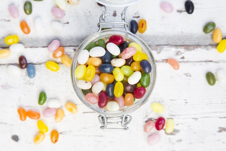 Glass of colourful sweet jellybeans on white wood