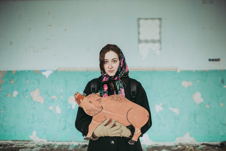 Image: Alisa Gorshenina poses with a cardboard boar she found in an abandoned shool in her native village of Yakshina