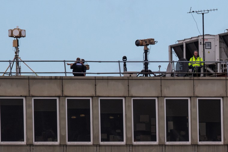 Image: Officials watch from a rooftop after the runway was reopened following a drone scare at London's Gatwick Airport in 2018