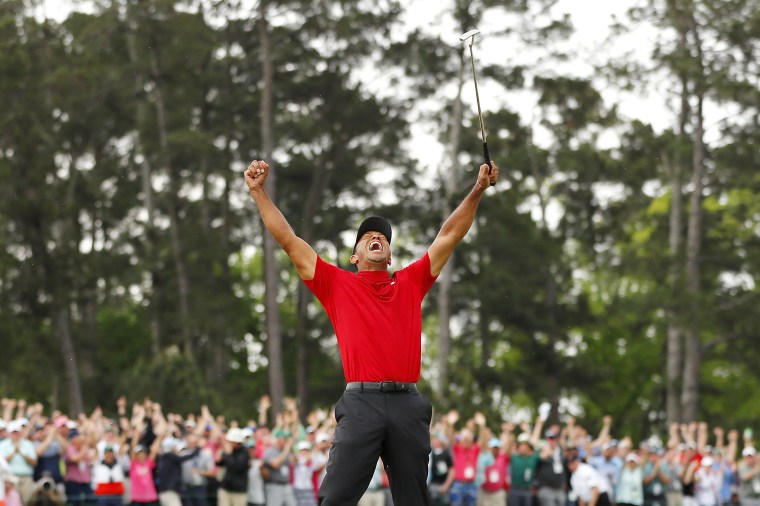 Image: Tiger Woods celebrates after sinking his putt on the 18th green