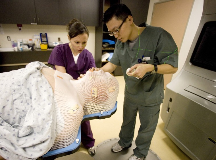 IMage: Radiation therapists Carla Cerase, left, and Vinh Truong help a patient get ready for radiation treatment at Princess Margaret Hospital in Toronto in 2007.