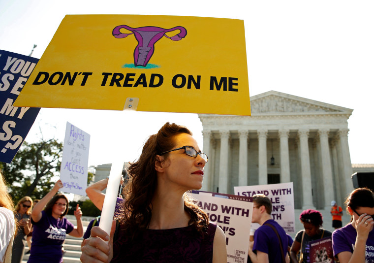 Demonstrators hold signs outside the U.S. Supreme Court in Washington