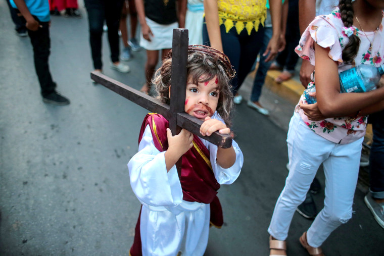 Image: A child dressed as Jesus Christ carries a wooden cross during the \"Jesus del gran poder\" procession in the colonial city of Granada